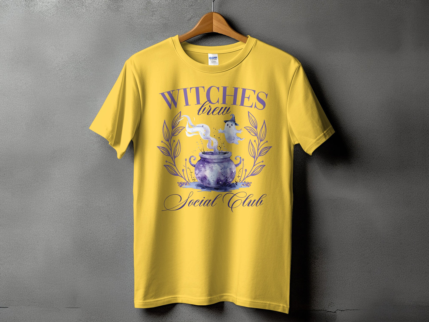 Yellow t-shirt with purple "Witches Brew Social Club" graphic featuring a cauldron and ghosts.