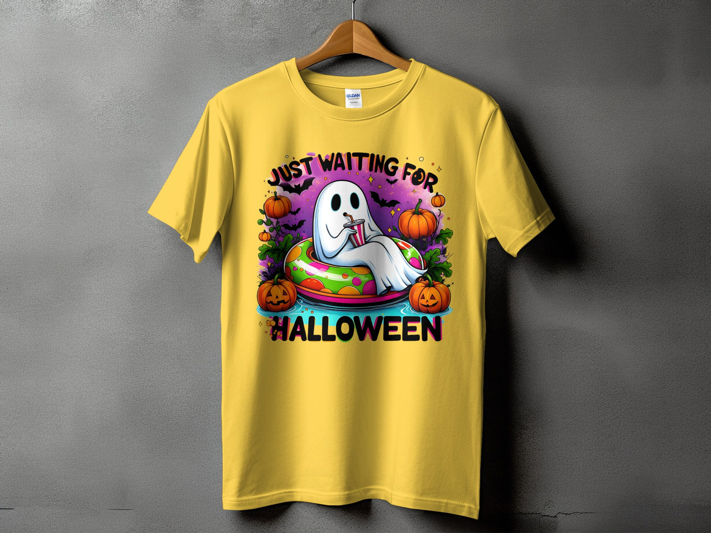 Yellow t-shirt with a ghost floating in a colorful inner tube, surrounded by pumpkins and bats.