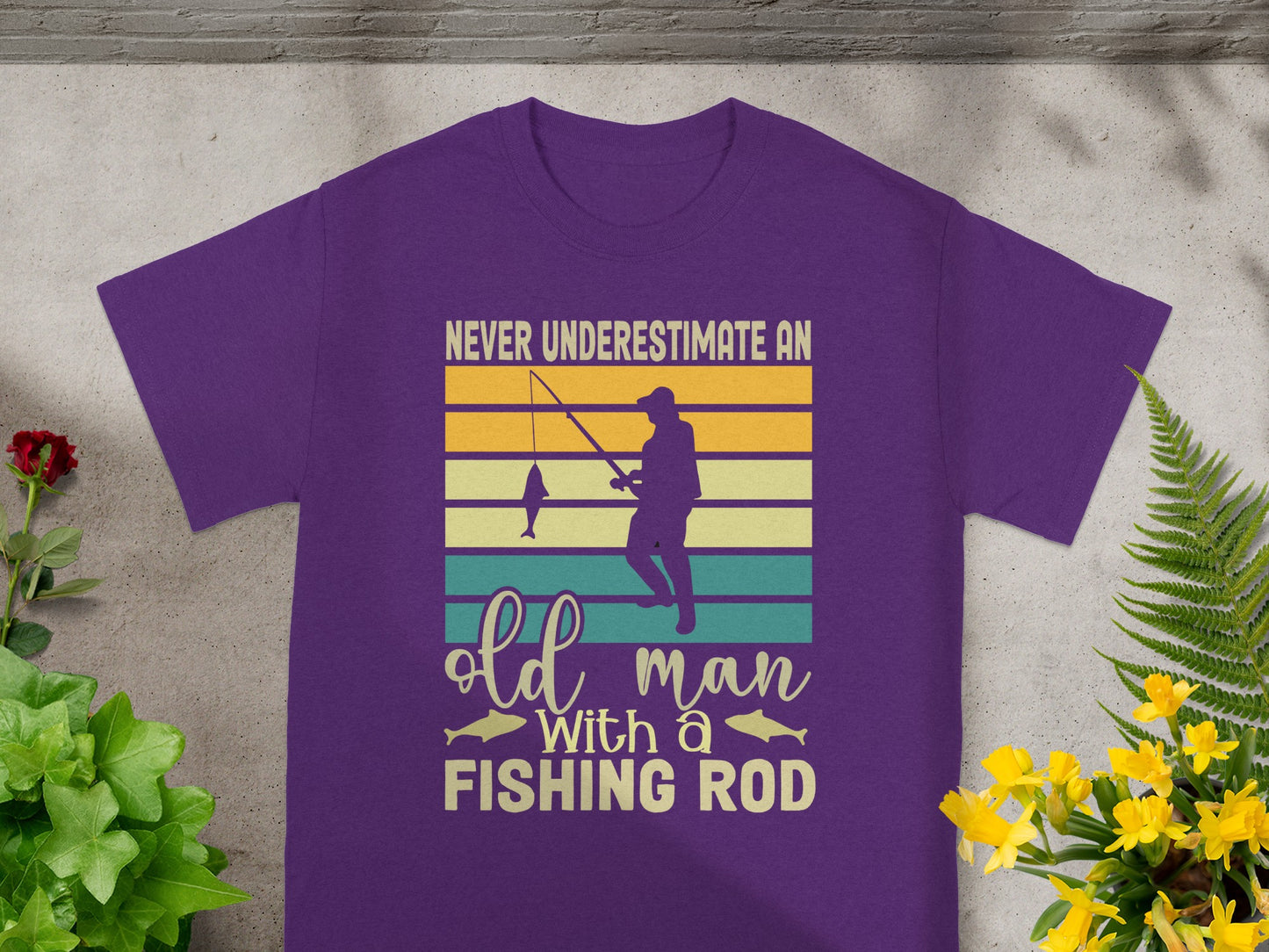 Purple t-shirt with text "Never Underestimate an Old Man With a Fishing Rod".