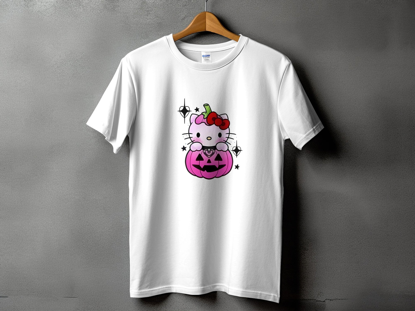 White t-shirt with pink Hello Kitty sitting on a Halloween pumpkin.
