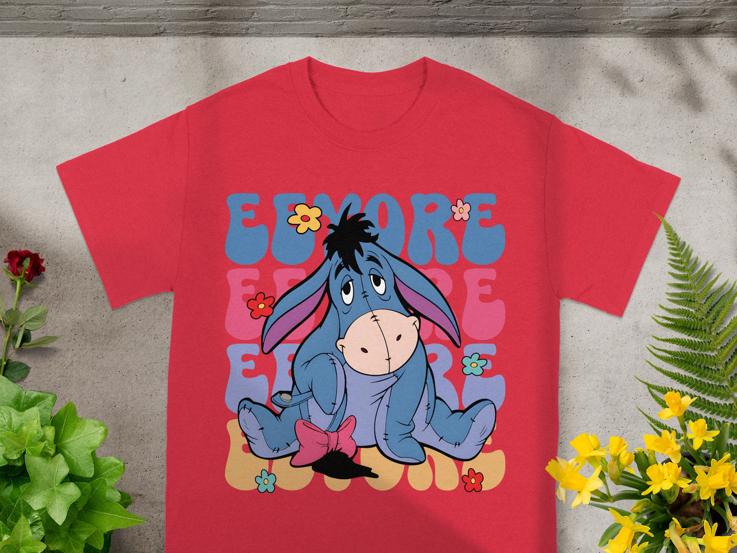 Eeyore sitting on colorful blocks with flowers, on a red t-shirt.
