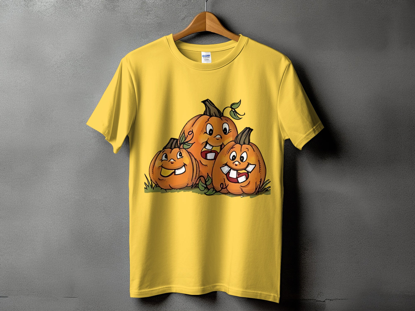 Yellow t-shirt with a cartoon graphic of three grinning pumpkins on grass.