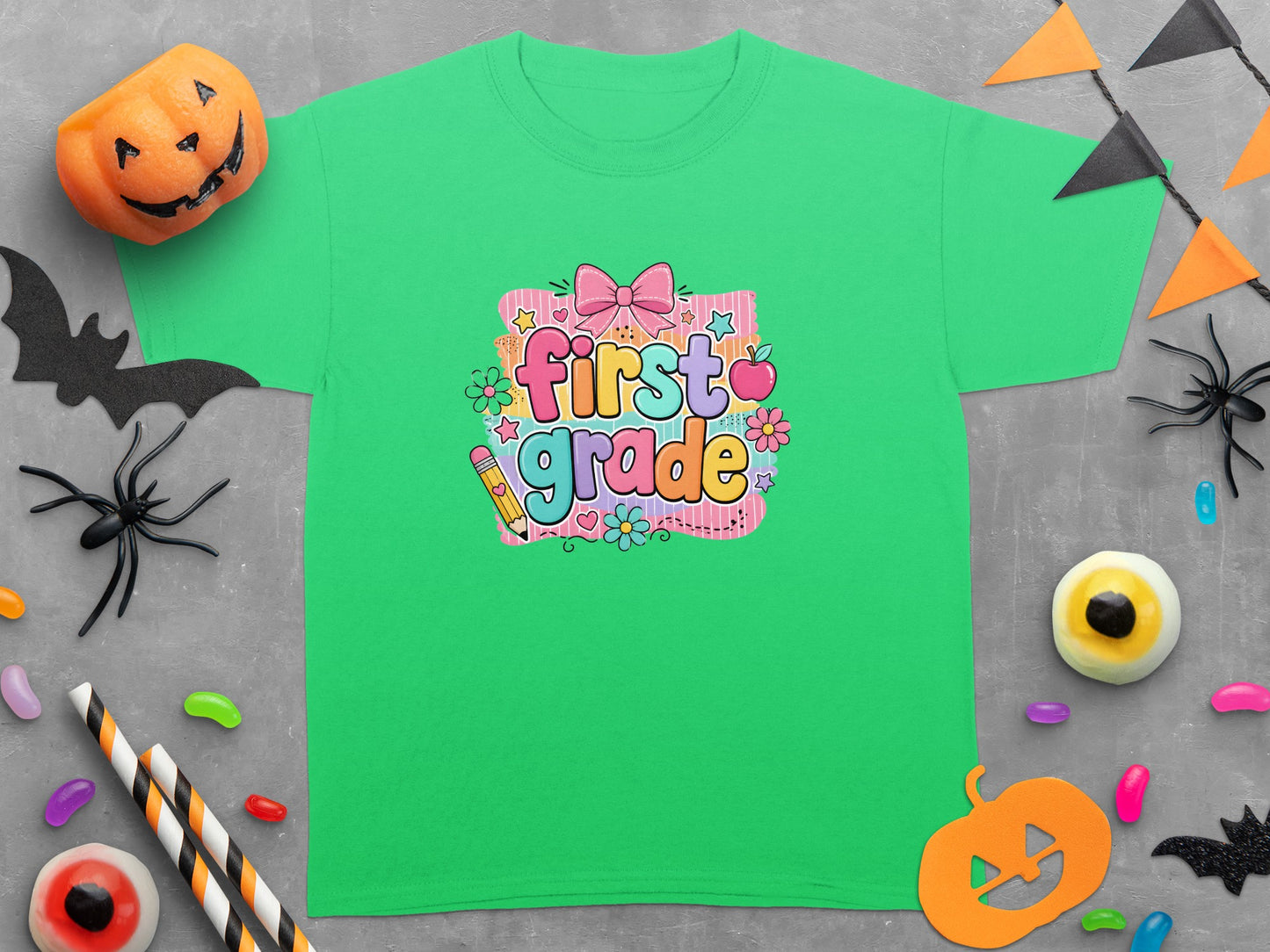 Green t-shirt with "first grade" text, festive school supplies, and Halloween decorations.