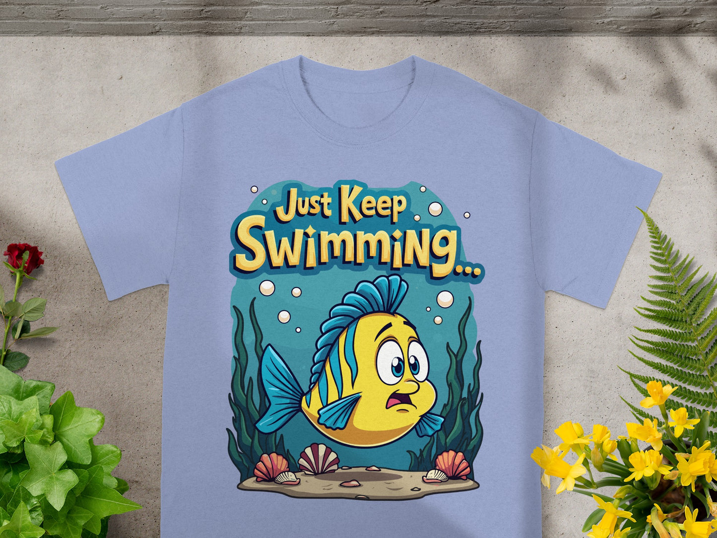 Light blue t-shirt with a yellow and blue striped fish saying "Just Keep Swimming..."