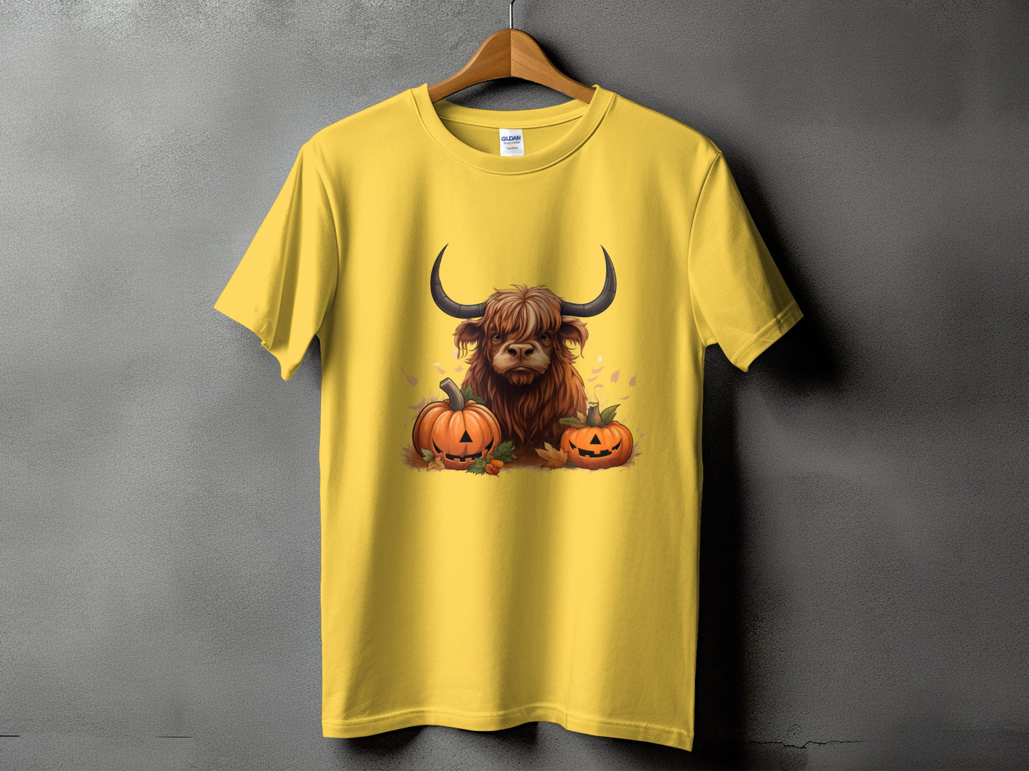 Yellow t-shirt with a graphic of a Highland cow and two jack-o'-lanterns.