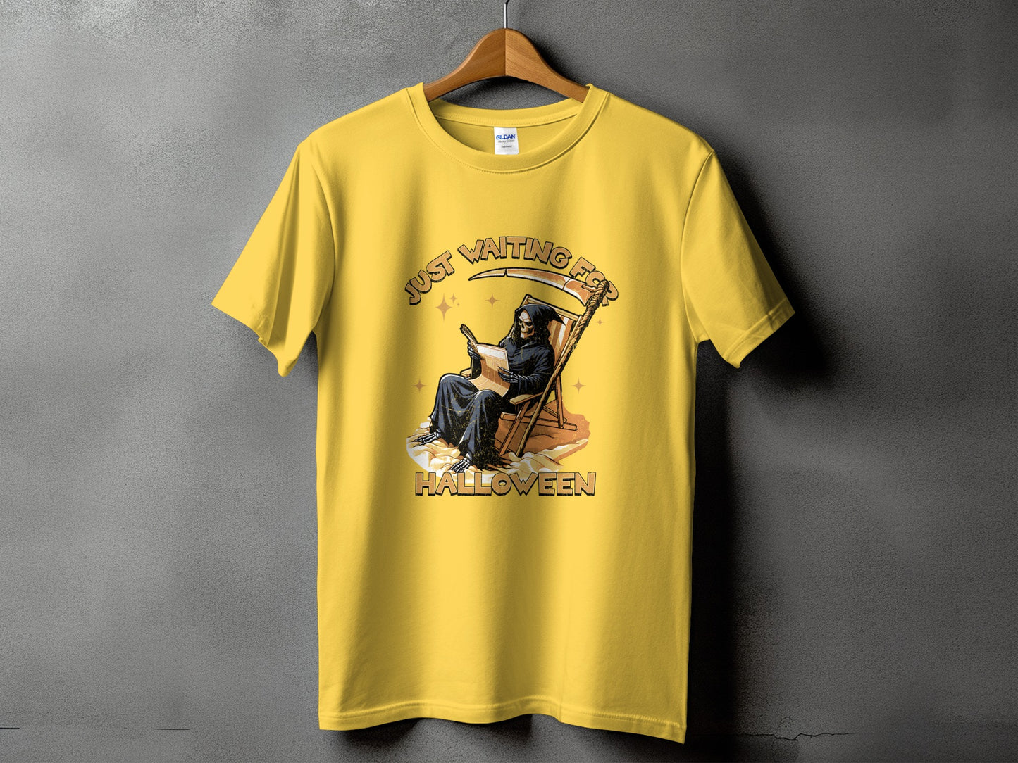 Yellow t-shirt with Grim Reaper reading on a beach chair, "Just Waiting For Halloween" text.