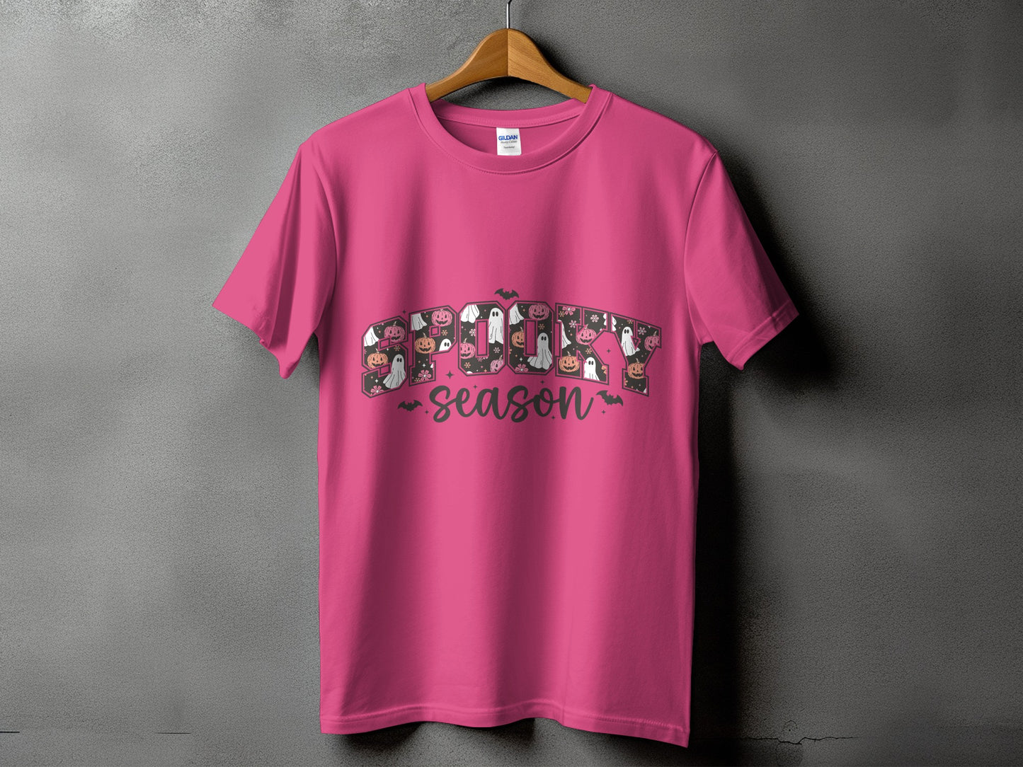 Pink t-shirt with "Spooky Season" text featuring Halloween graphics like ghosts and pumpkins.
