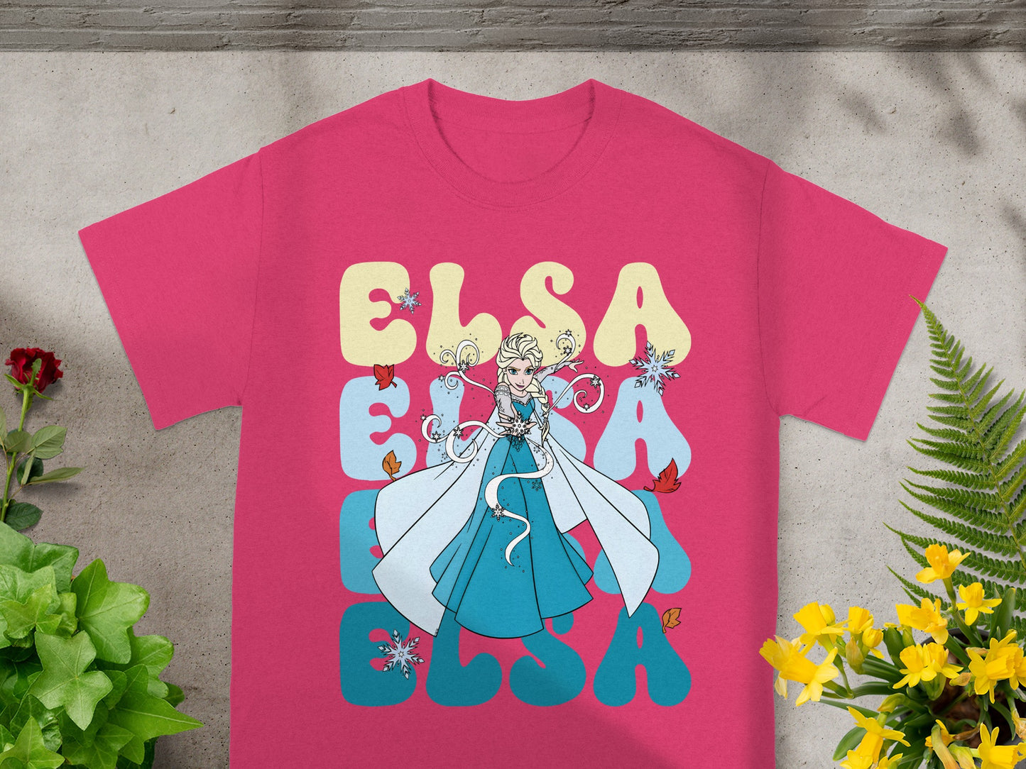 Pink t-shirt with Elsa from Frozen surrounded by large stylized text.