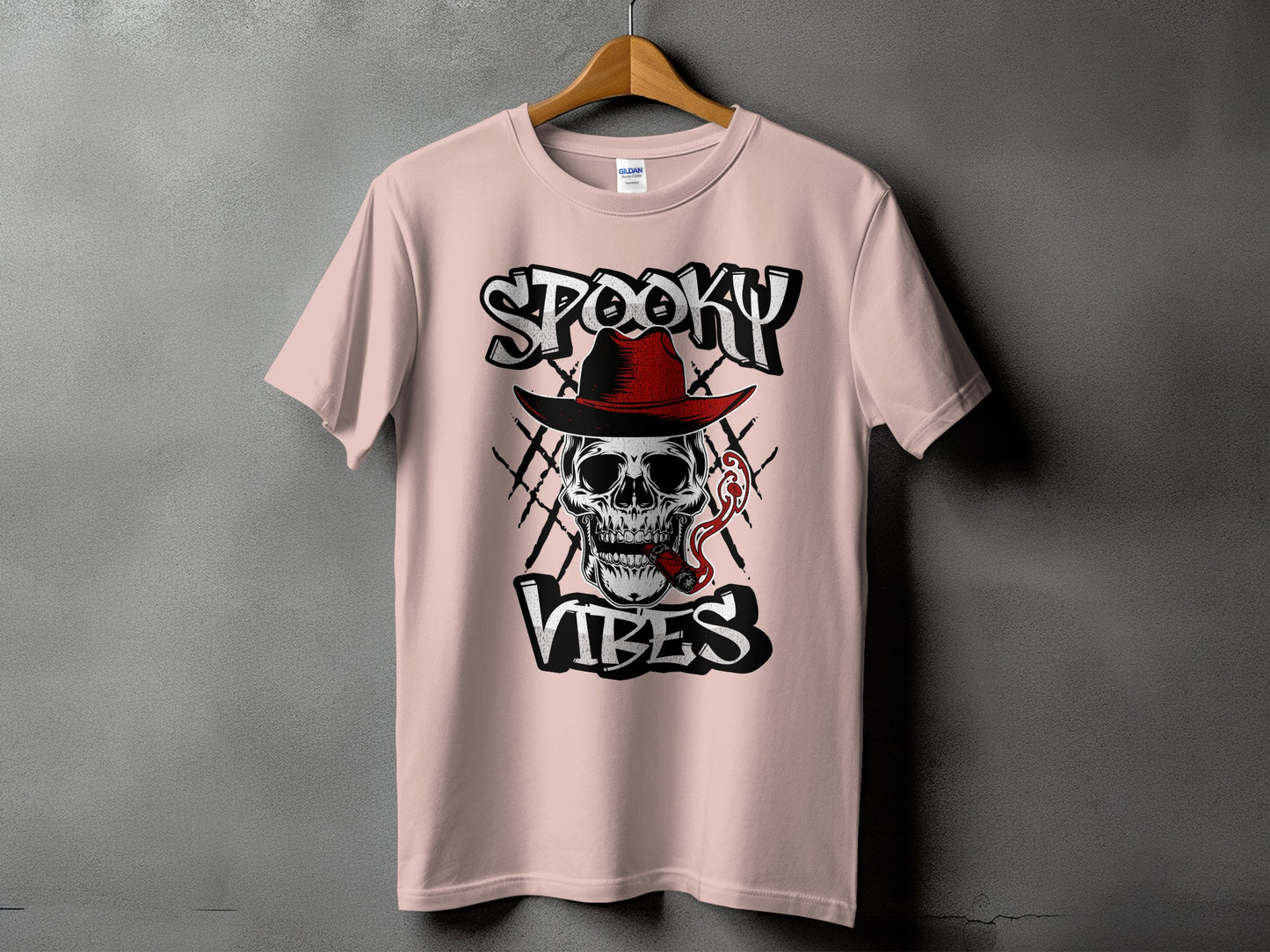 Pink t-shirt with a skull wearing a red hat, smoking a cigar, and the words "Spooky Vibes."