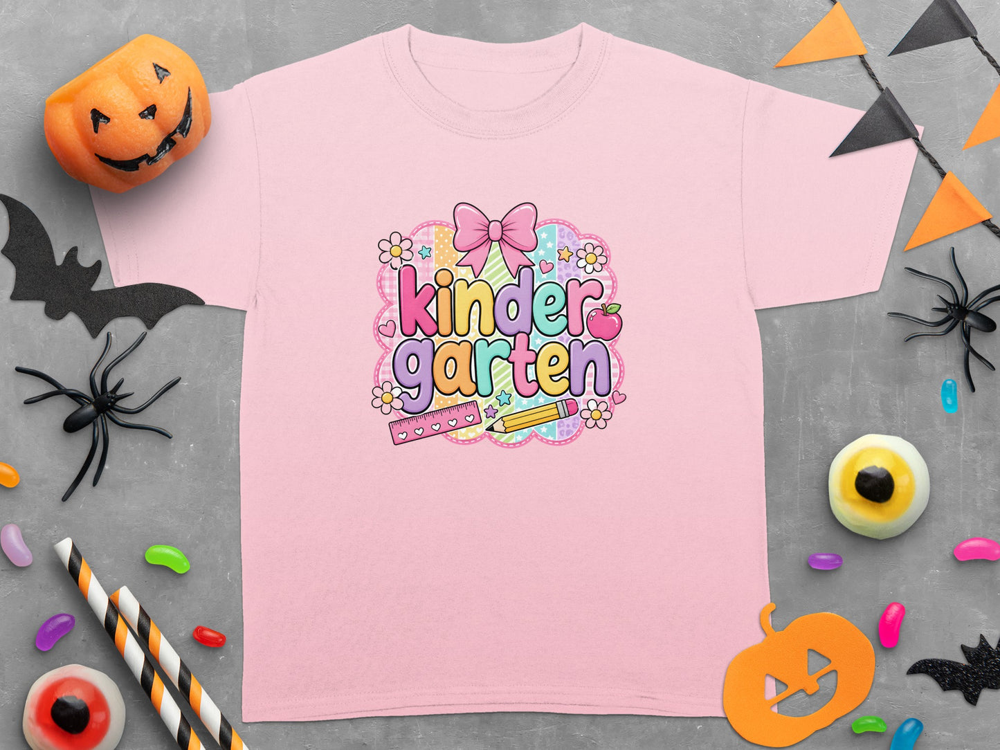 Pink t-shirt with "kindergarten" graphic, Halloween decorations scattered around.