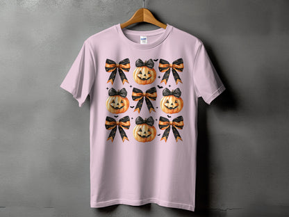 Pink t-shirt with a repeated pattern of Halloween pumpkins and bows.