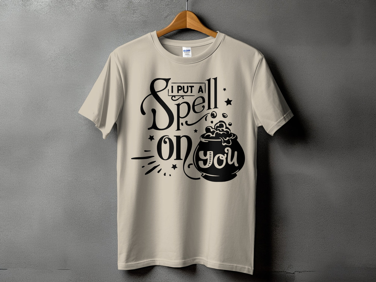 Light tan t-shirt with black text "I PUT A SPELL on YOU" and a cauldron graphic.