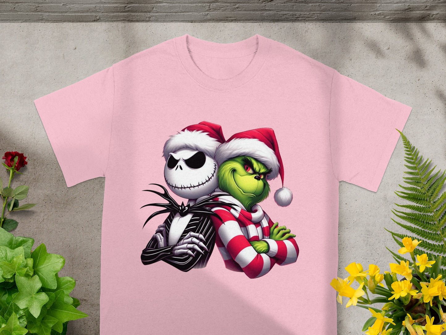 Jack Skellington and The Grinch wearing Santa hats and a scarf on a pink shirt