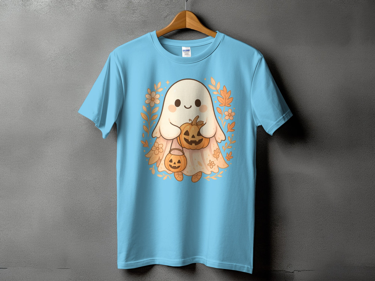 Light blue t-shirt with a cute ghost holding pumpkins and surrounded by fall leaves.
