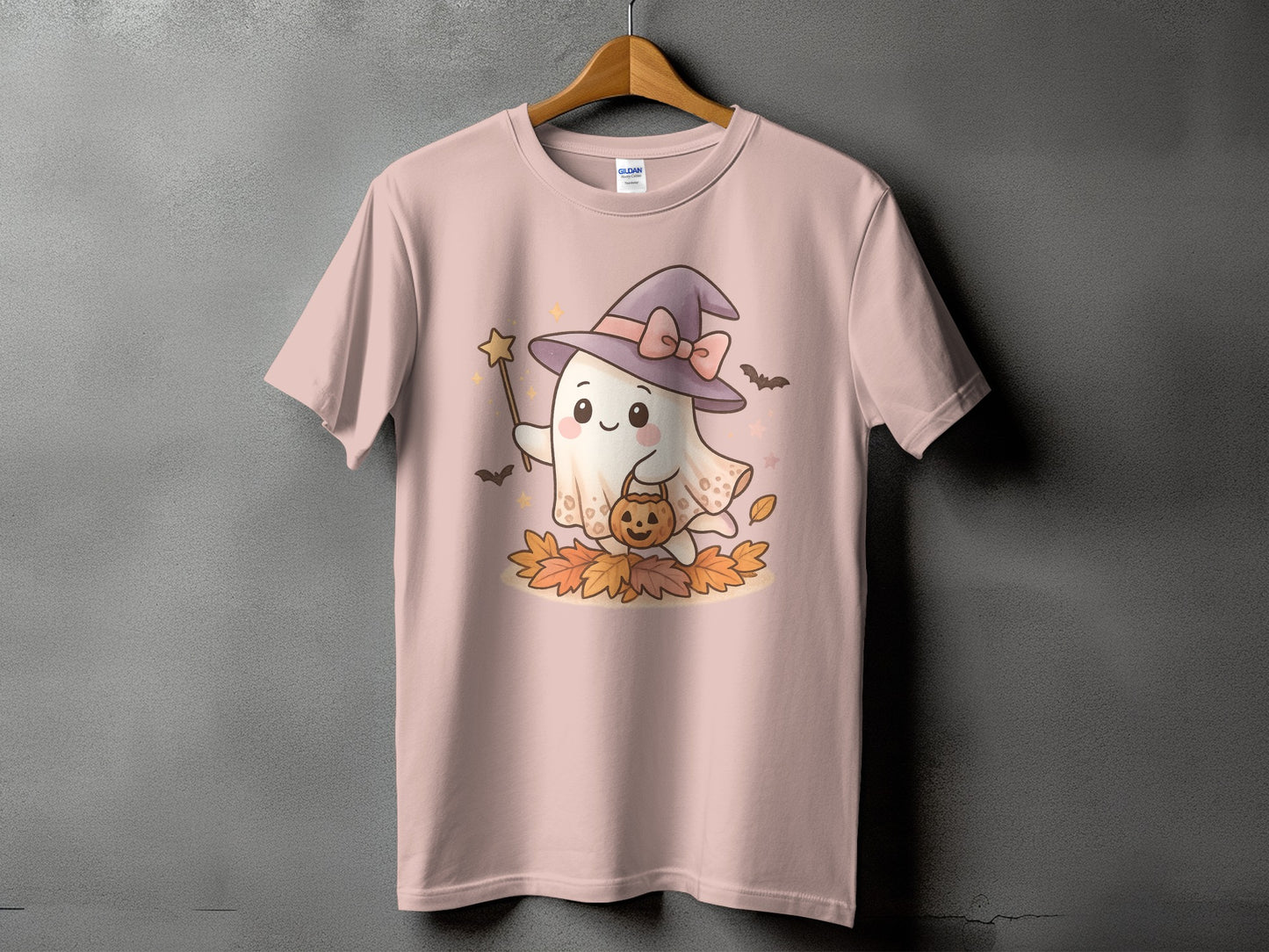 Pink t-shirt featuring a cute ghost wearing a witch hat holding a pumpkin and a wand.