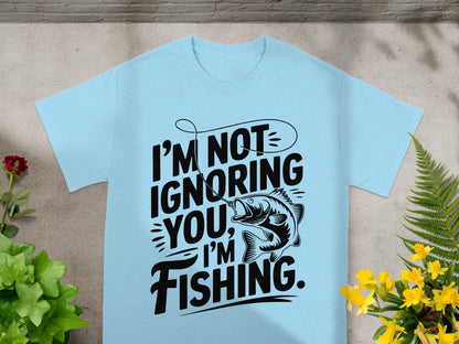 Light blue t-shirt with black text that reads "I'M NOT IGNORING YOU, I'M FISHING" and a graphic of a fish.
