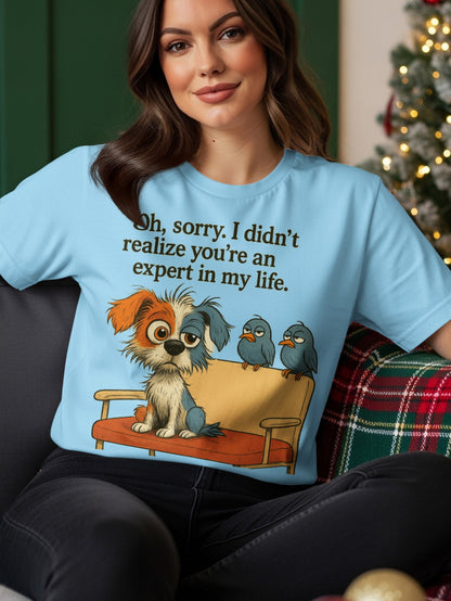 Light blue t-shirt with a dog and birds on a couch with text "Oh, sorry. I didn't realize you're an expert in my life."