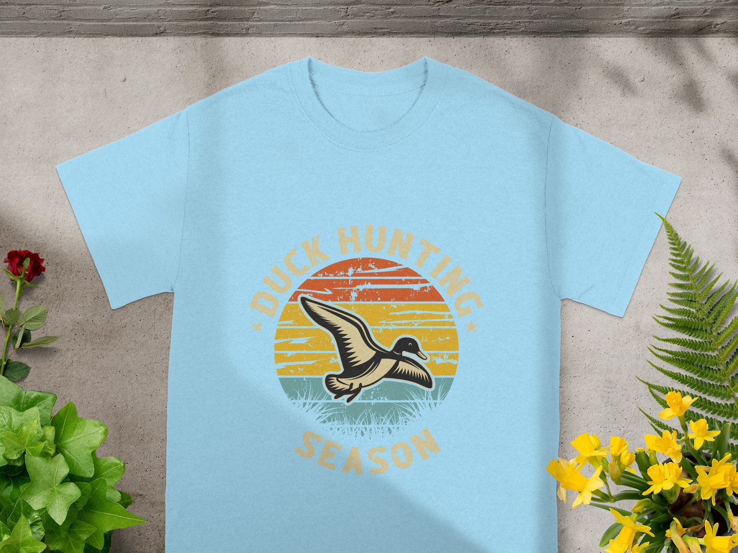 Light blue t-shirt with a circular duck hunting graphic and sunset design.