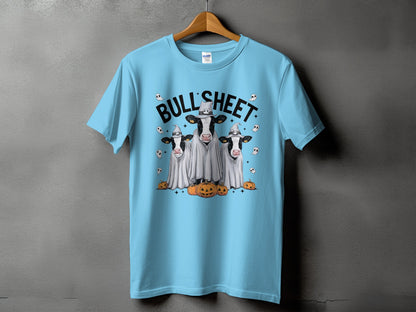 Light blue t-shirt with graphic of three cows in ghost costumes and pumpkins.