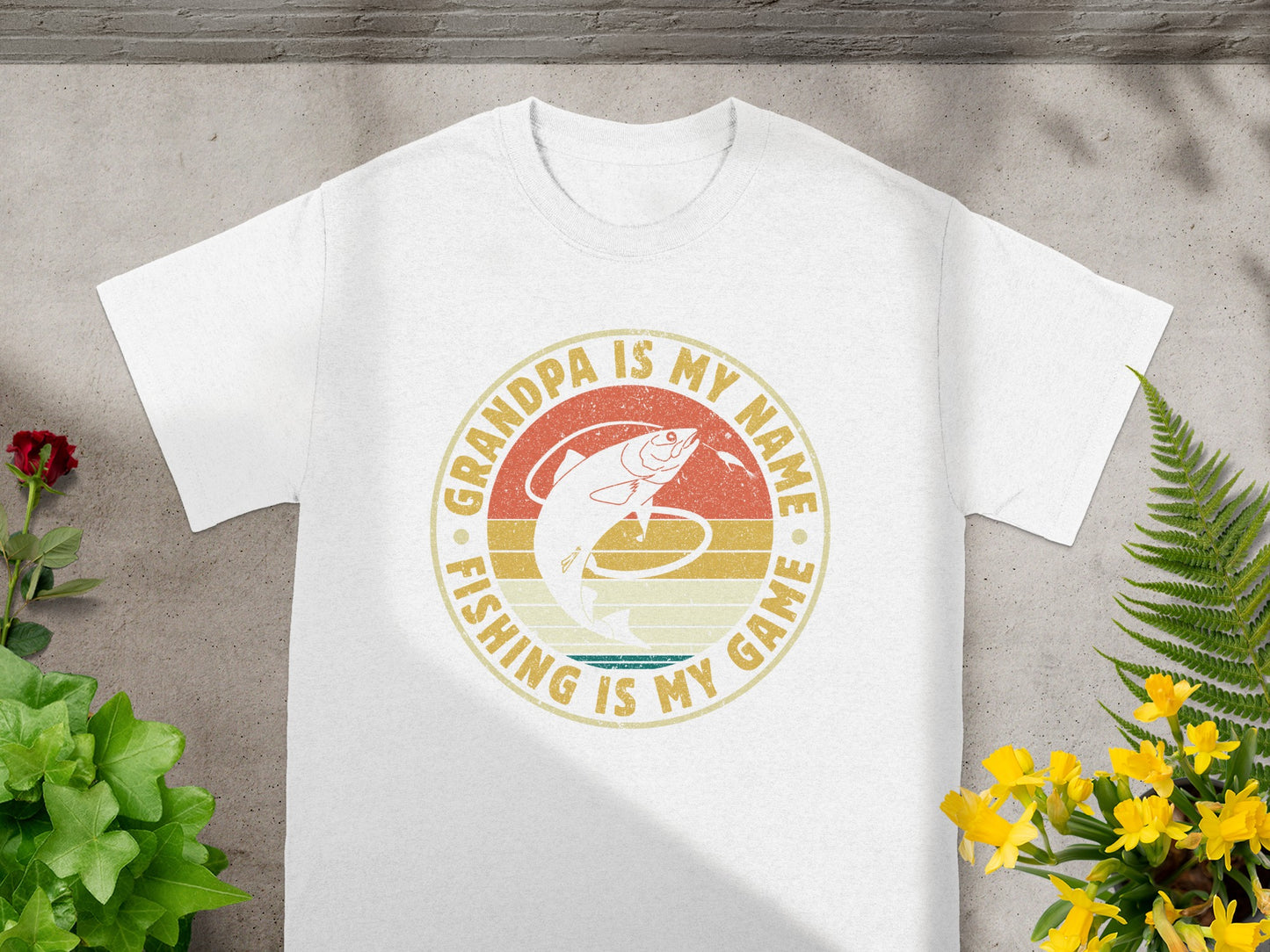 White t-shirt with "Grandpa is my name, fishing is my game" text and fish graphic.