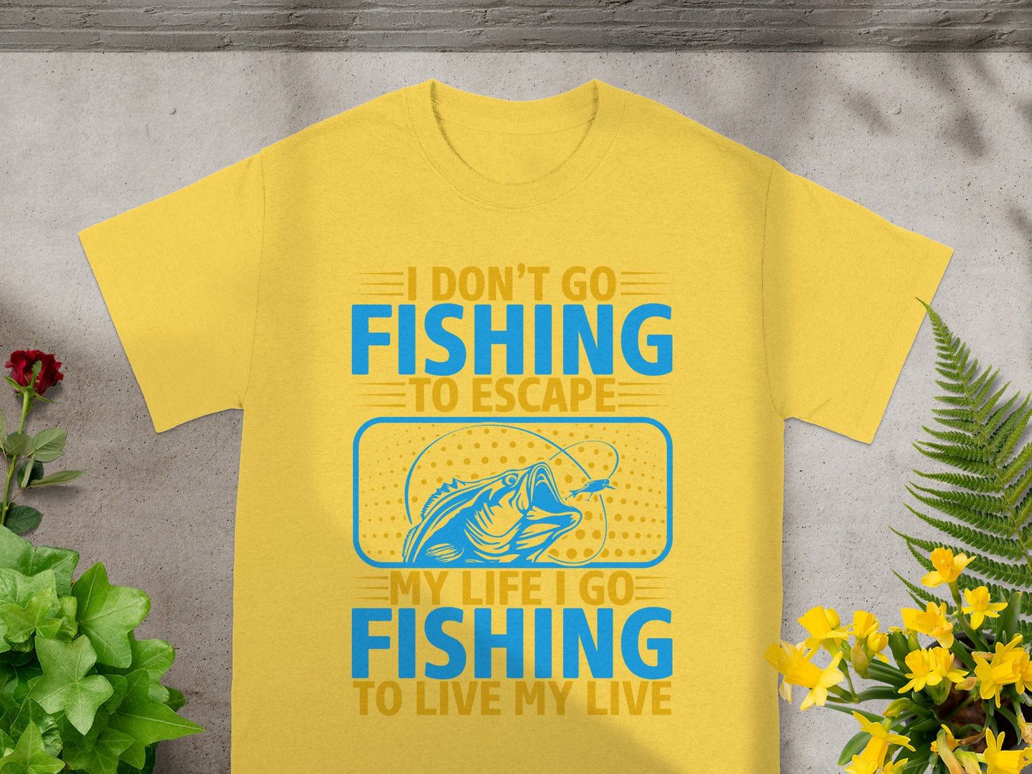 Yellow t-shirt with blue text and a fishing graphic: "I DON'T GO FISHING TO ESCAPE MY LIFE I GO FISHING TO LIVE MY LIVE".