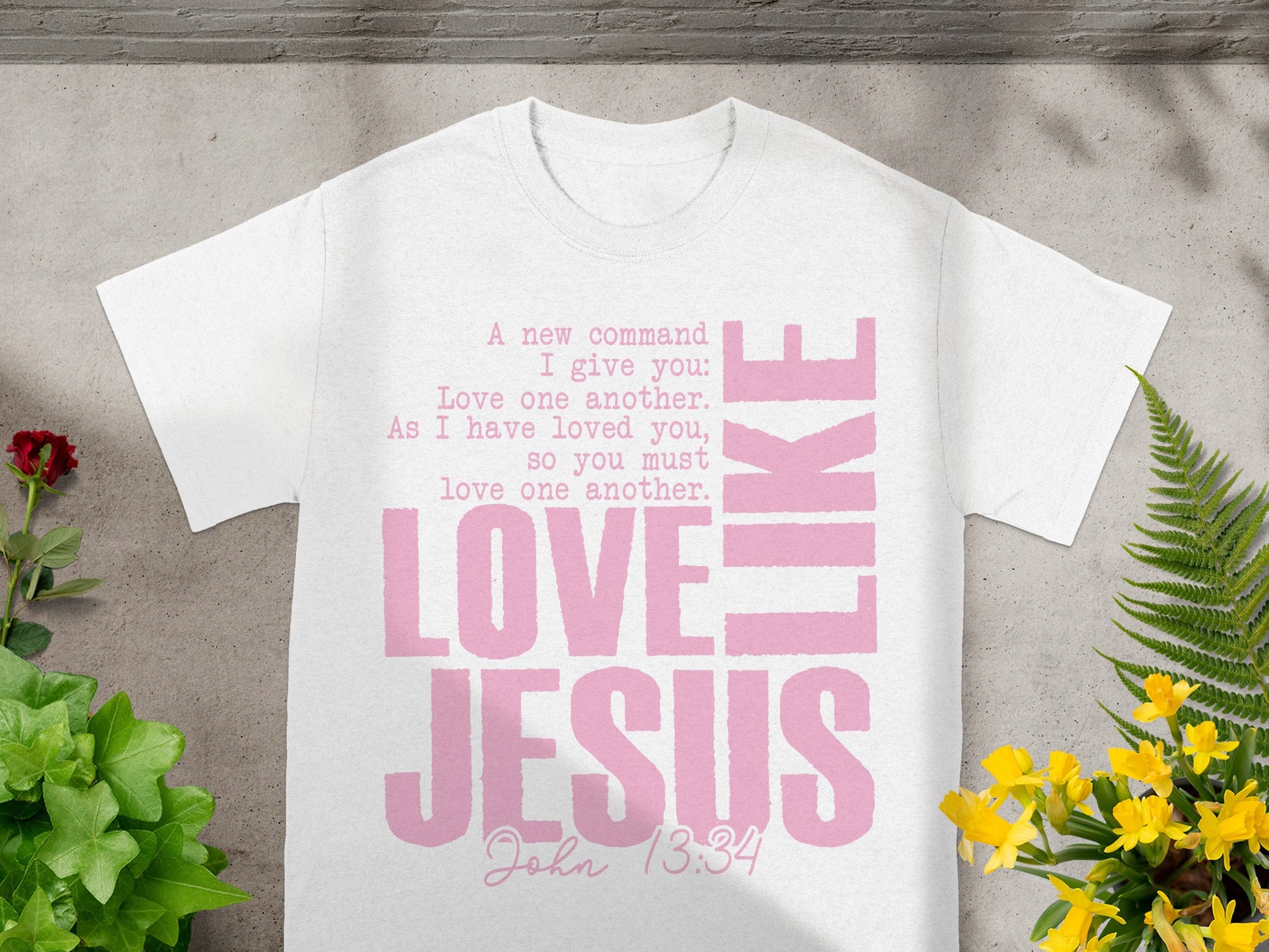 White t-shirt with pink text: "Love Jesus" and a Bible verse.
