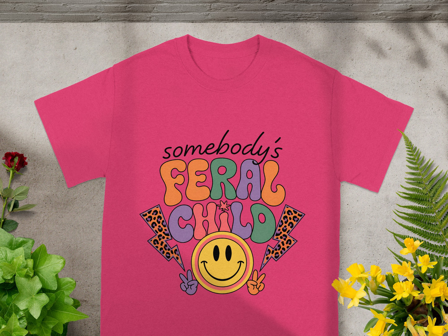 Pink t-shirt with "somebody's FERAL CHILD" text and smiley face graphics.