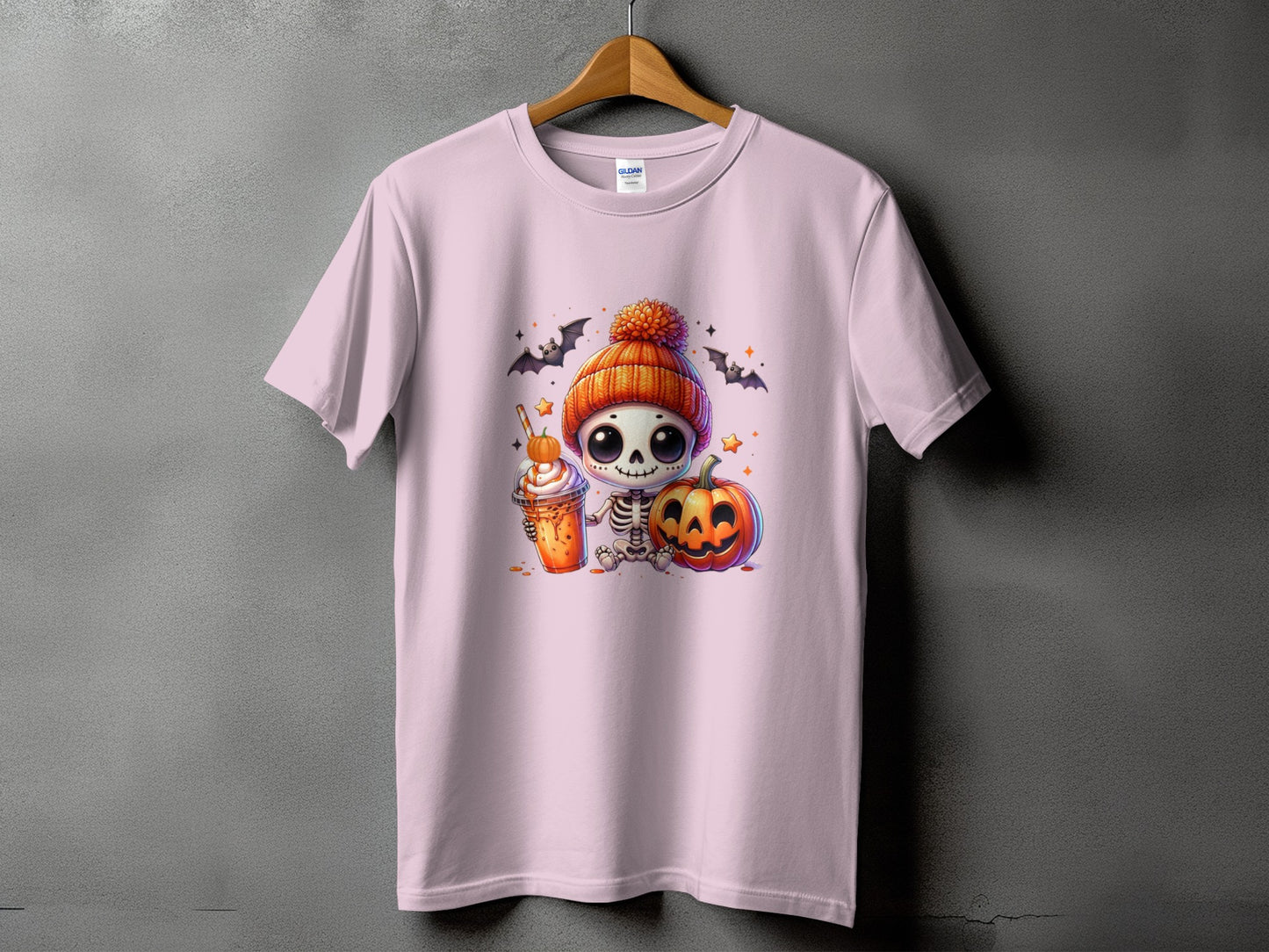 Pink t-shirt with a cartoon skeleton holding a pumpkin spice latte and a pumpkin.