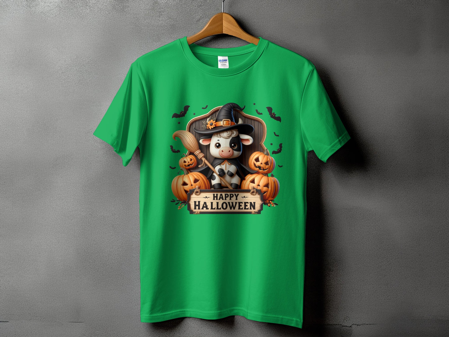 Green t-shirt with cartoon cow in witch hat, broom, and pumpkins, says "Happy Halloween".