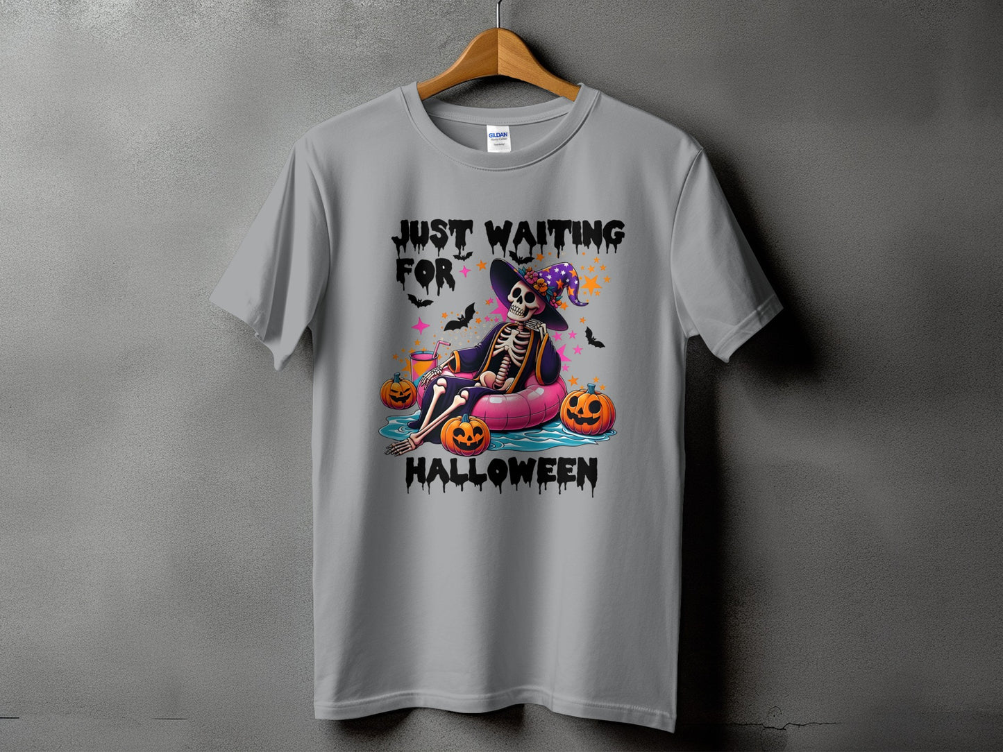 Skeleton wearing witch hat floating with pumpkins, text "JUST WAITING FOR HALLOWEEN".
