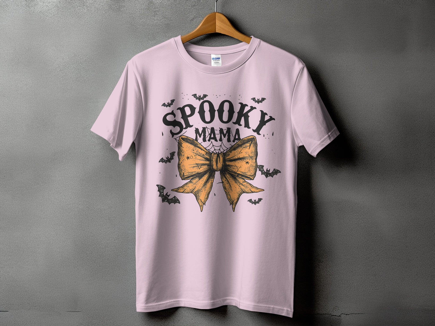 Pink t-shirt with "Spooky Mama" text, an orange bow, and bats.