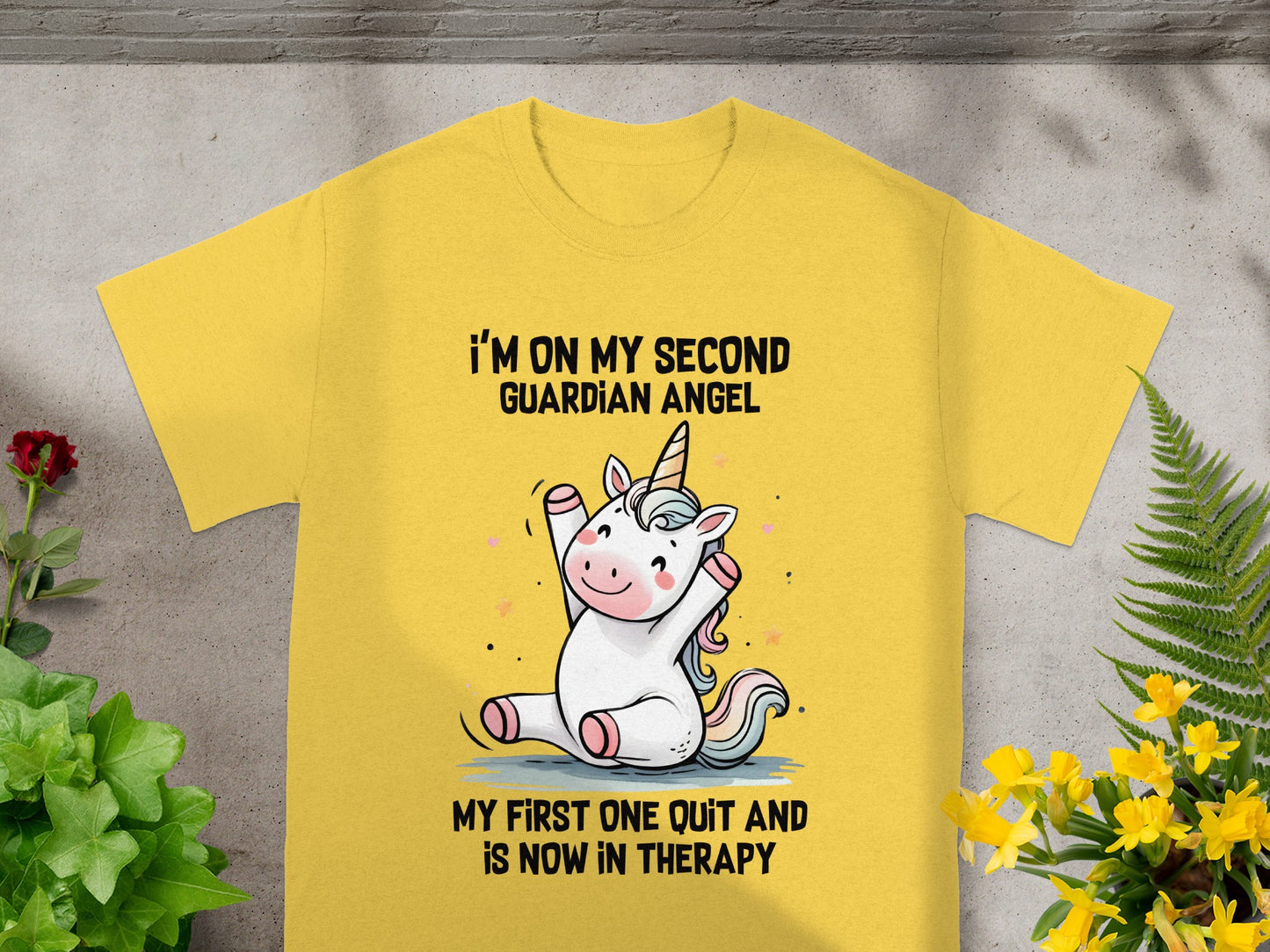 Yellow t-shirt with a unicorn graphic and text: "I'm on my second guardian angel. My first one quit and is now in therapy."