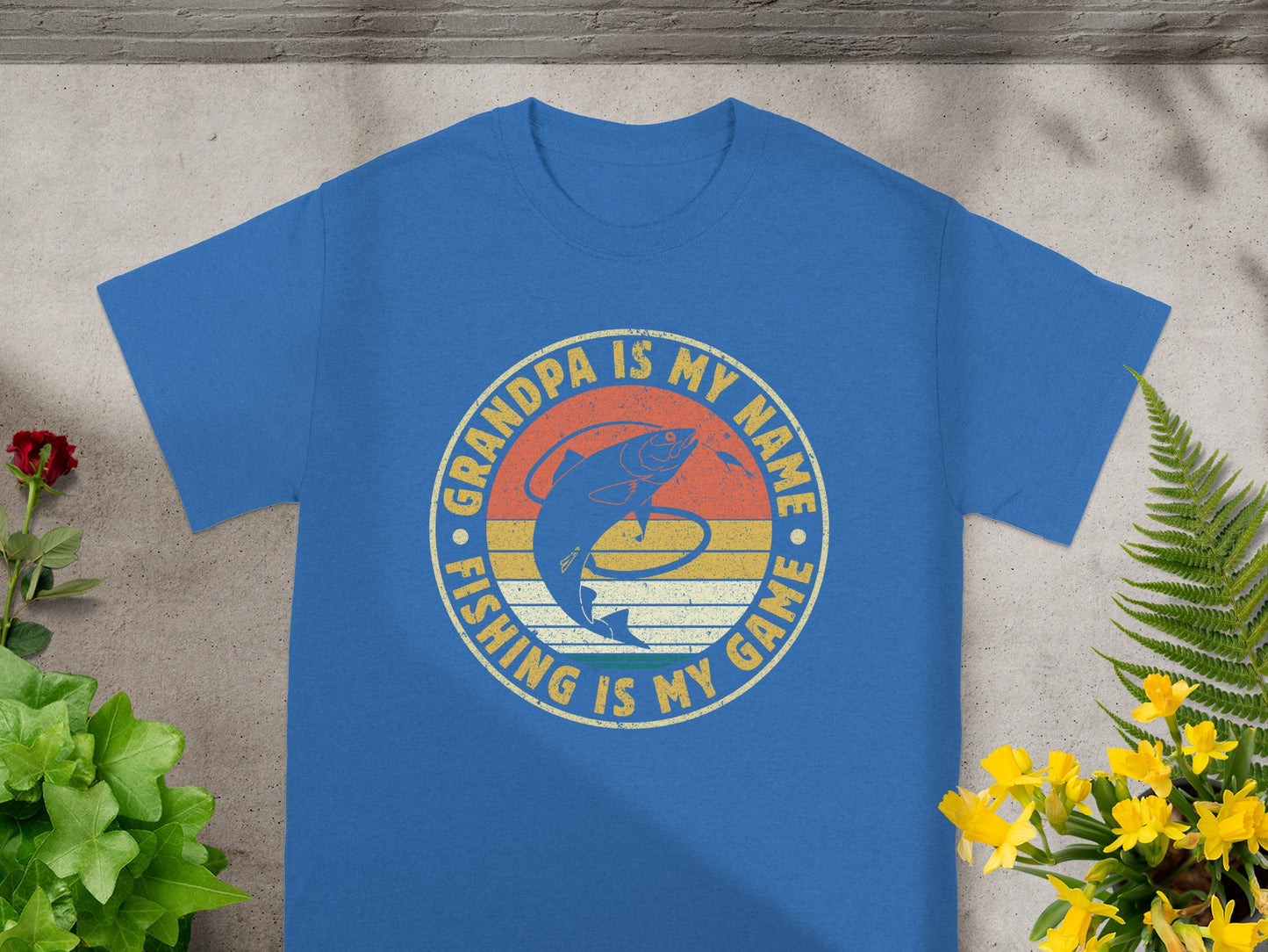 Blue t-shirt with a circular graphic that says "Grandpa is my name. Fishing is my game."