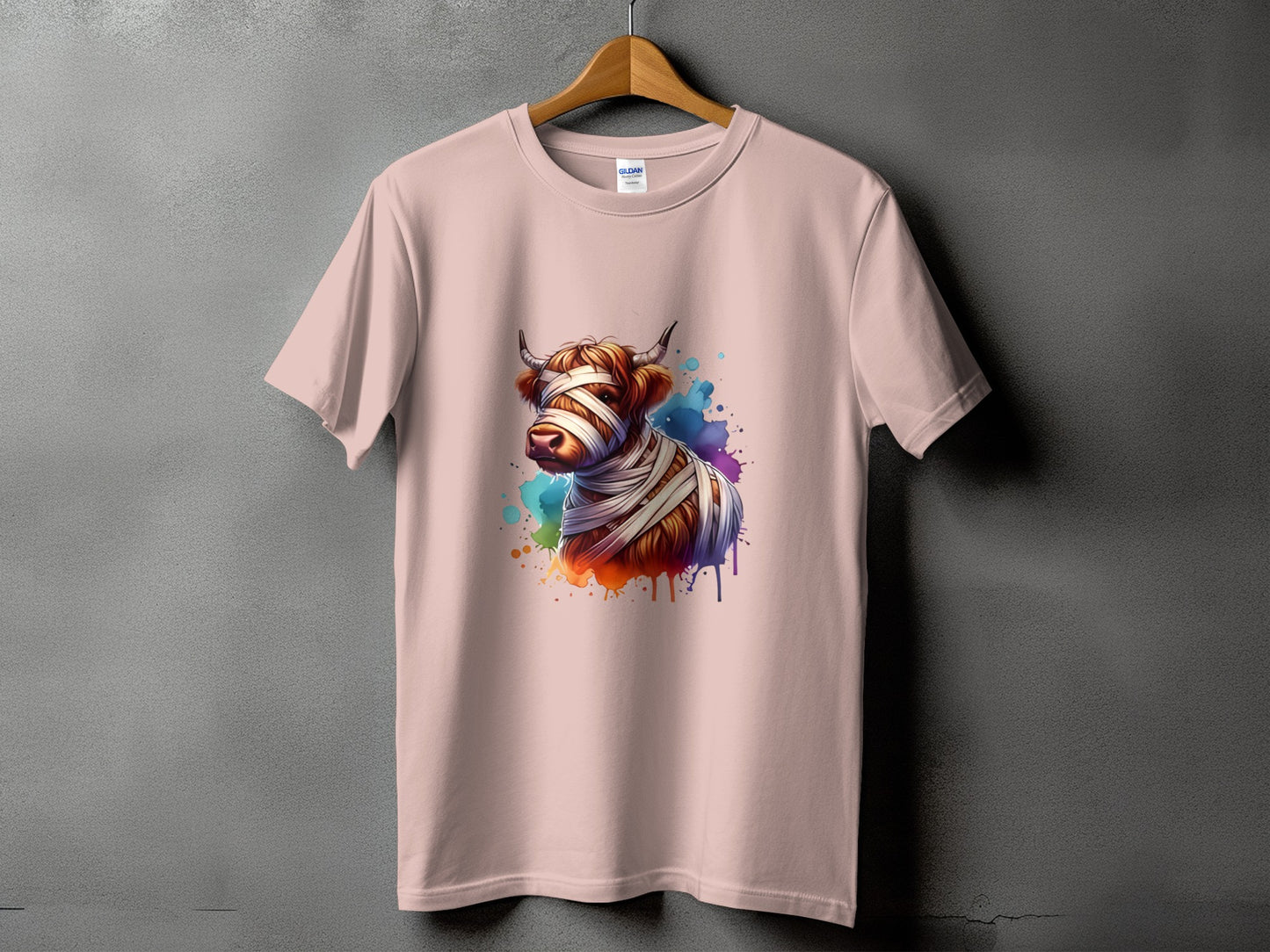 Pink t-shirt with a watercolor highland cow wrapped in bandages graphic.