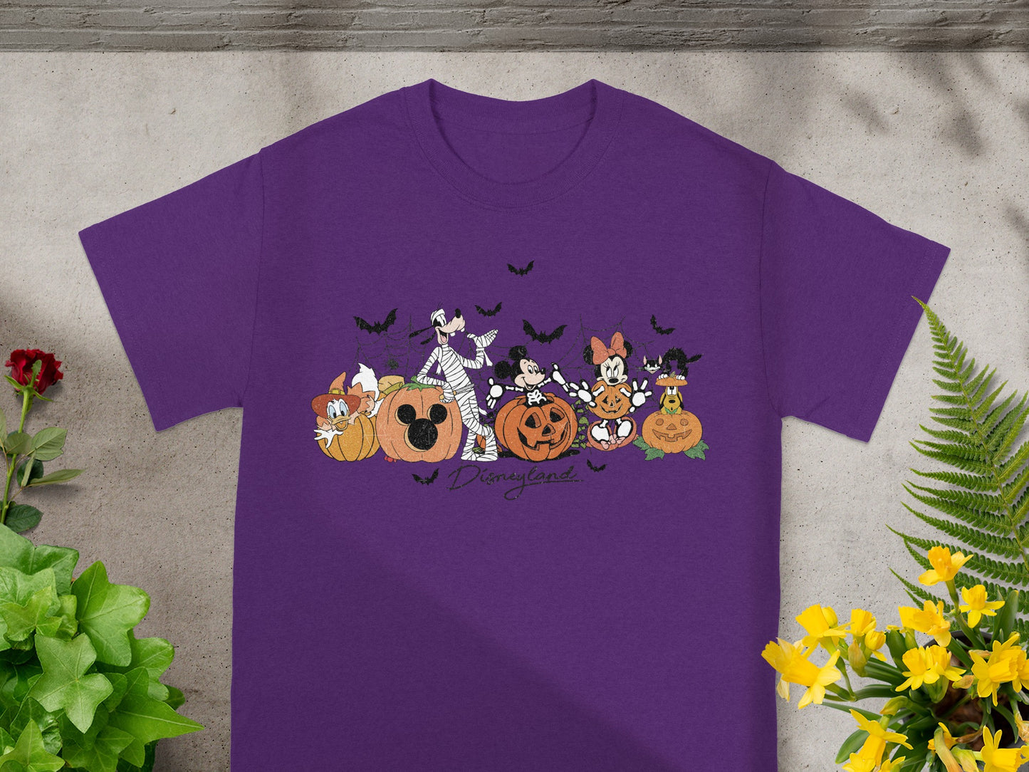 Purple t-shirt featuring Disney characters with pumpkins and bats, text "Disneyland".