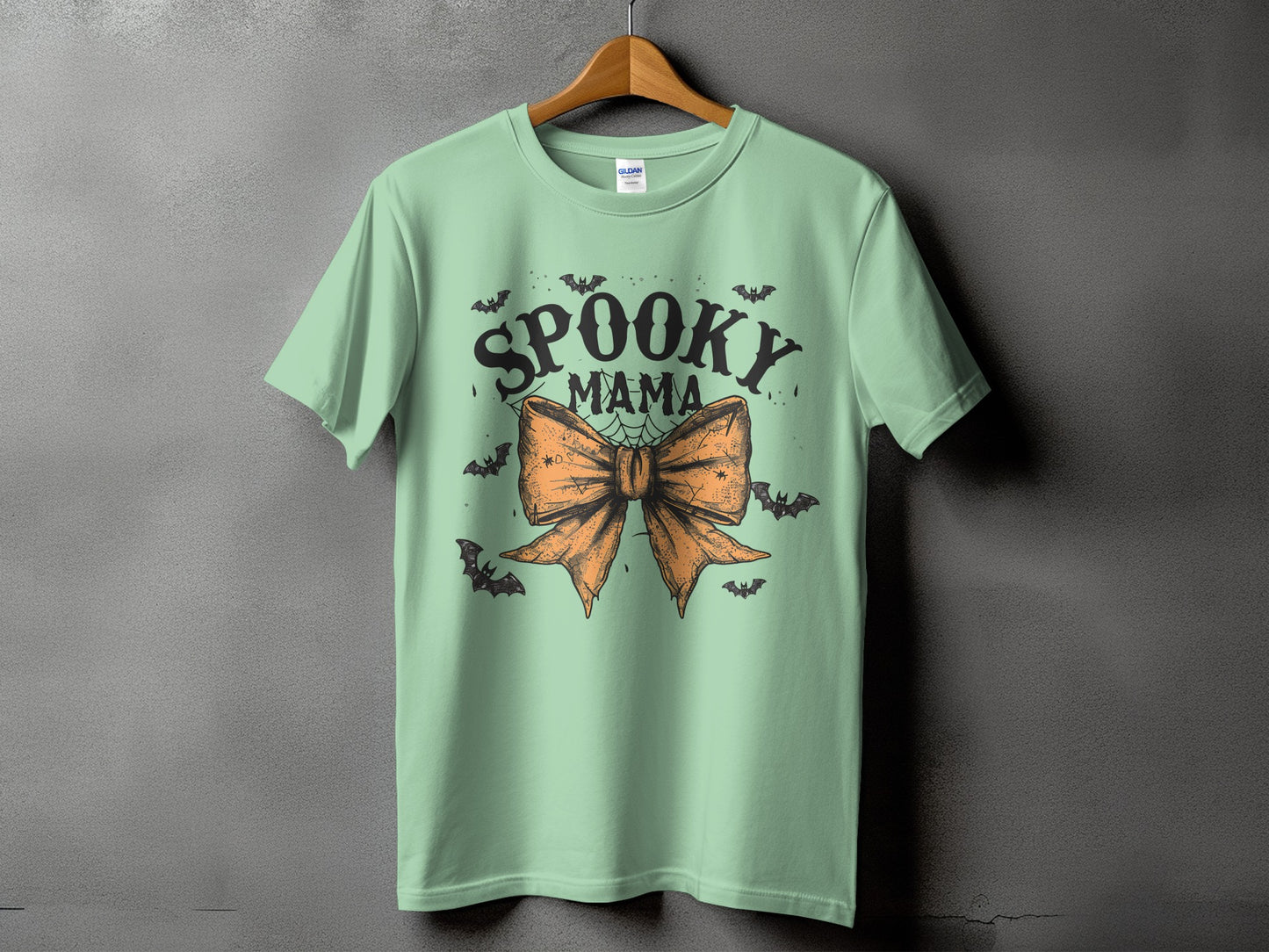 Mint green t-shirt with "Spooky Mama" text and orange bow graphic.