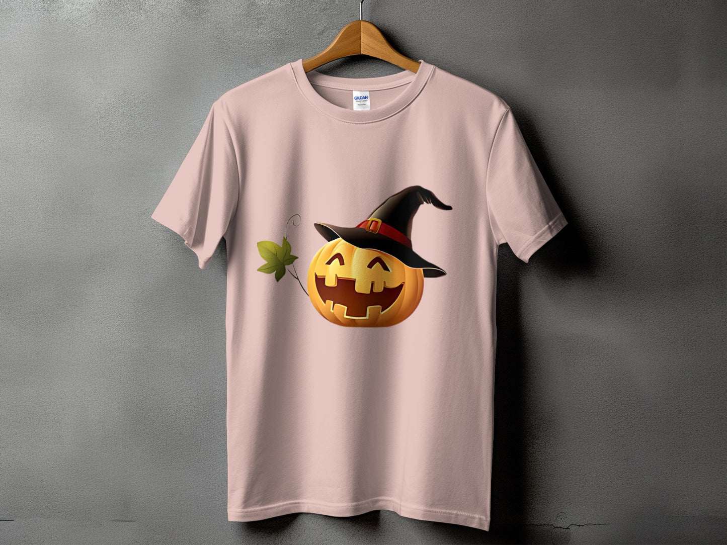 Pink t-shirt with smiling jack-o'-lantern wearing a witch hat and a leaf.