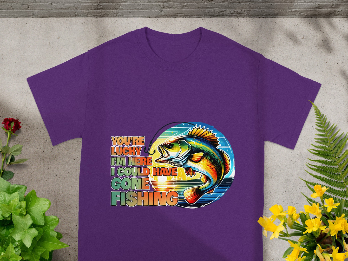 Purple t-shirt with a colorful fish, fishing hook, sunset, and text.