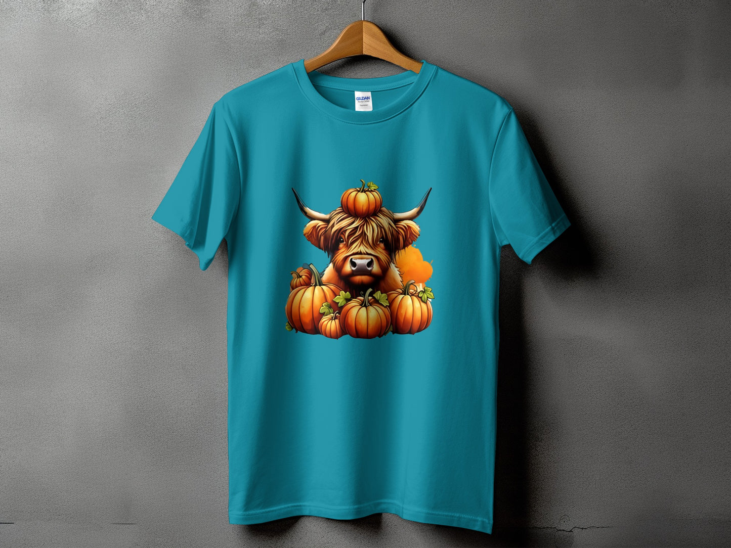 Teal t-shirt with a Highland cow graphic surrounded by pumpkins.