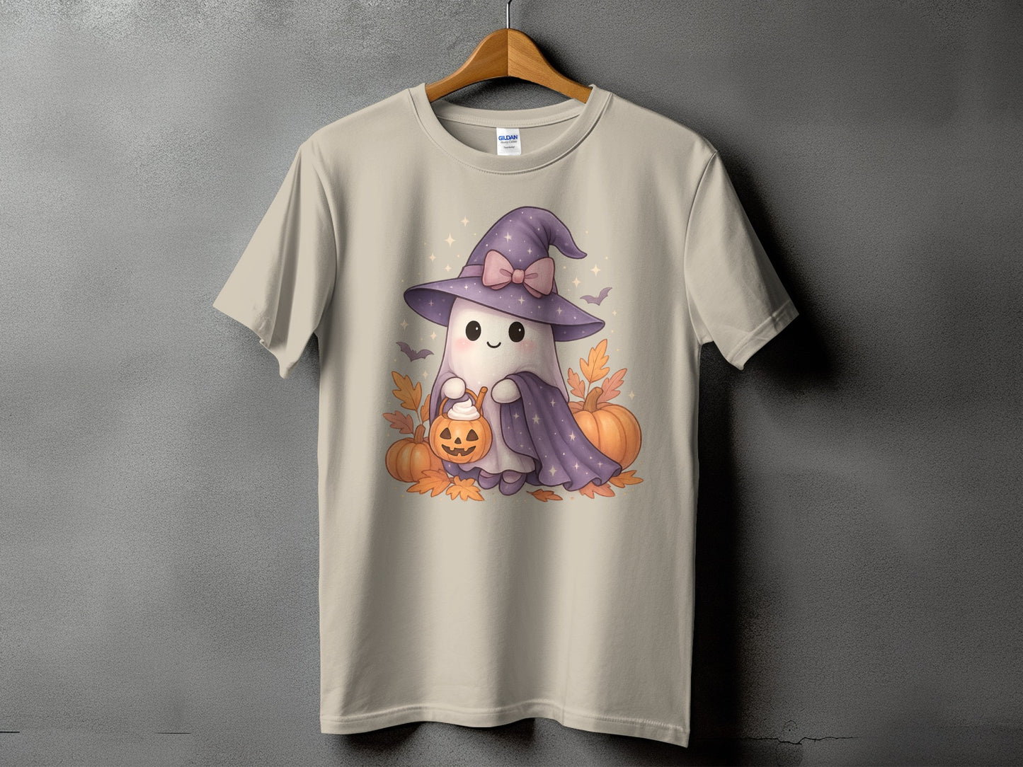 Light tan t-shirt with a cute ghost wearing a witch hat and holding a jack-o'-lantern.