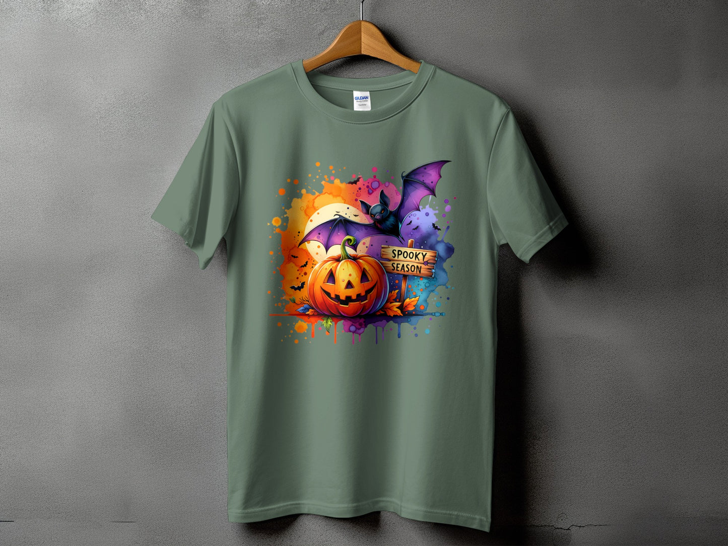 Green t-shirt with a watercolor Halloween graphic featuring a jack-o-lantern and bat.