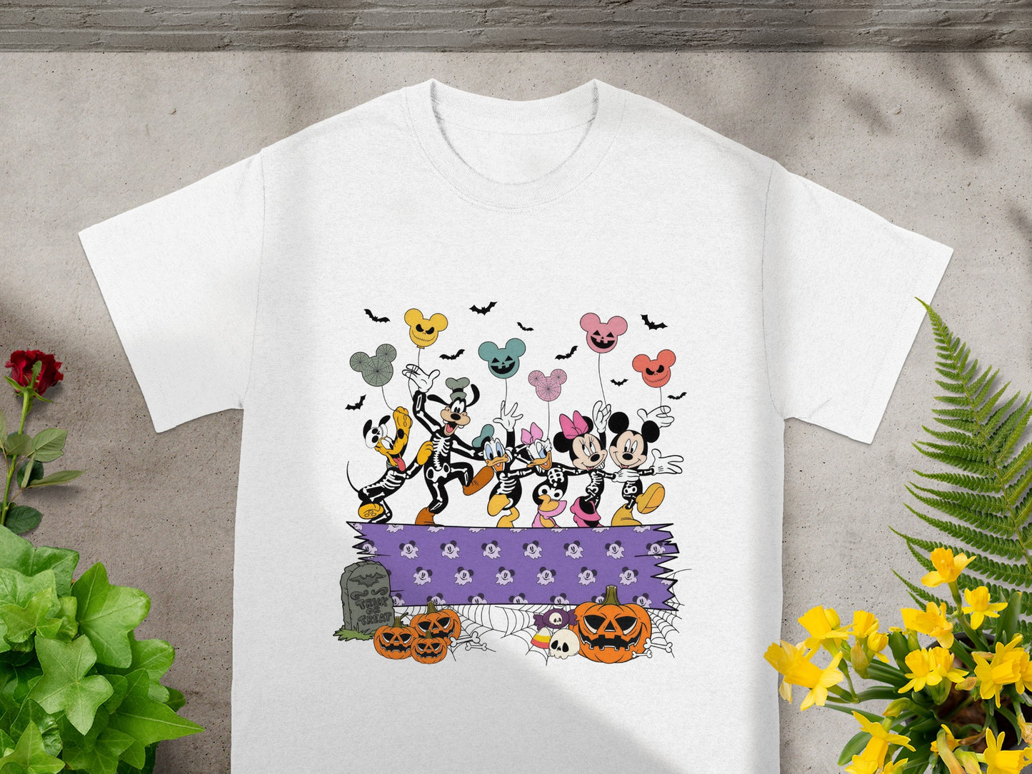 Disney characters in skeleton costumes dance with Halloween-themed balloons above pumpkins and a tombstone.