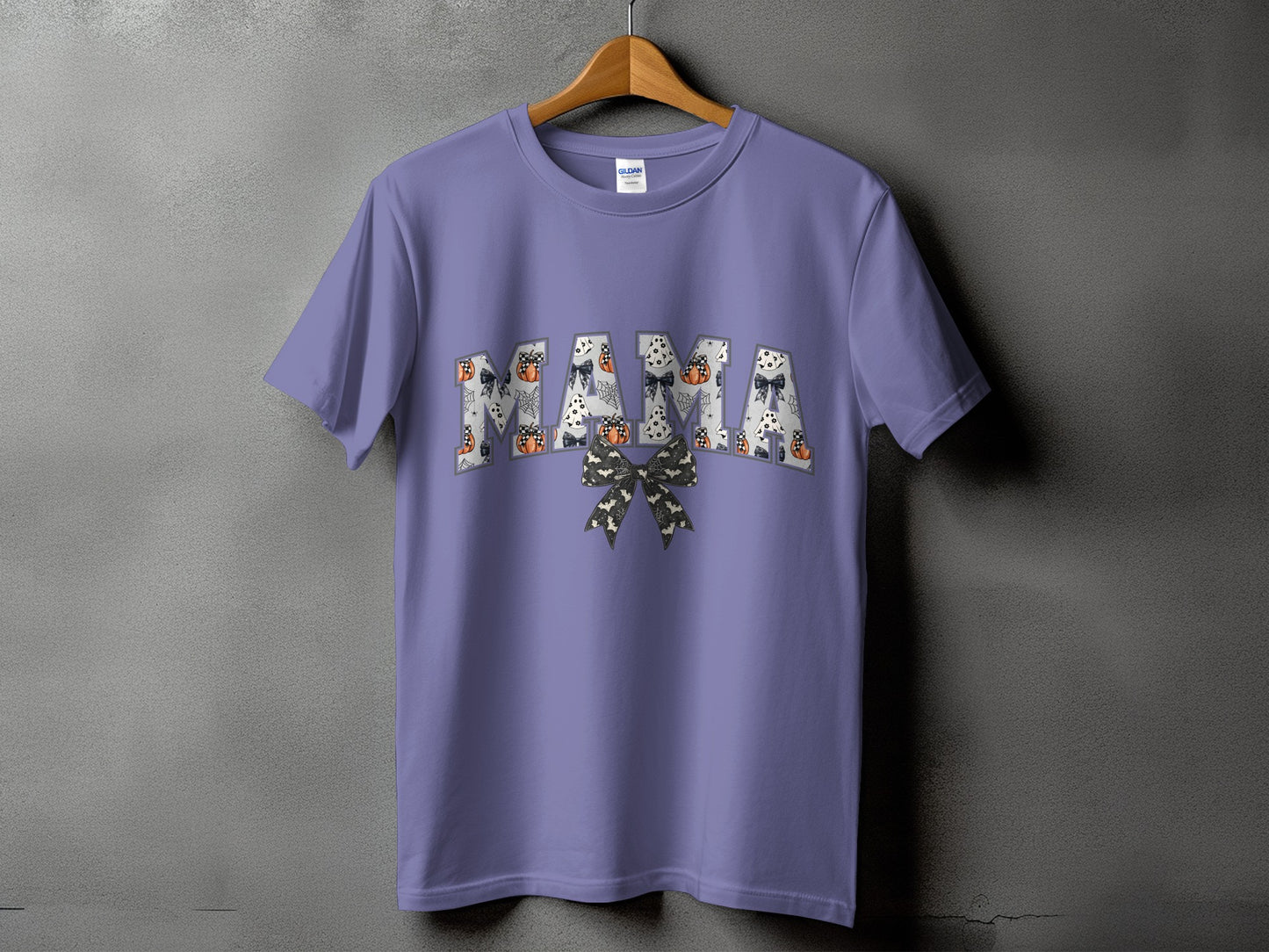 Purple t-shirt with "MAMA" text in Halloween-themed patterns and a bow.
