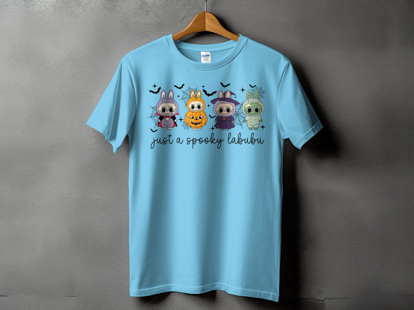 Light blue t-shirt with four cartoon characters dressed for Halloween and text "just a spooky labubu".
