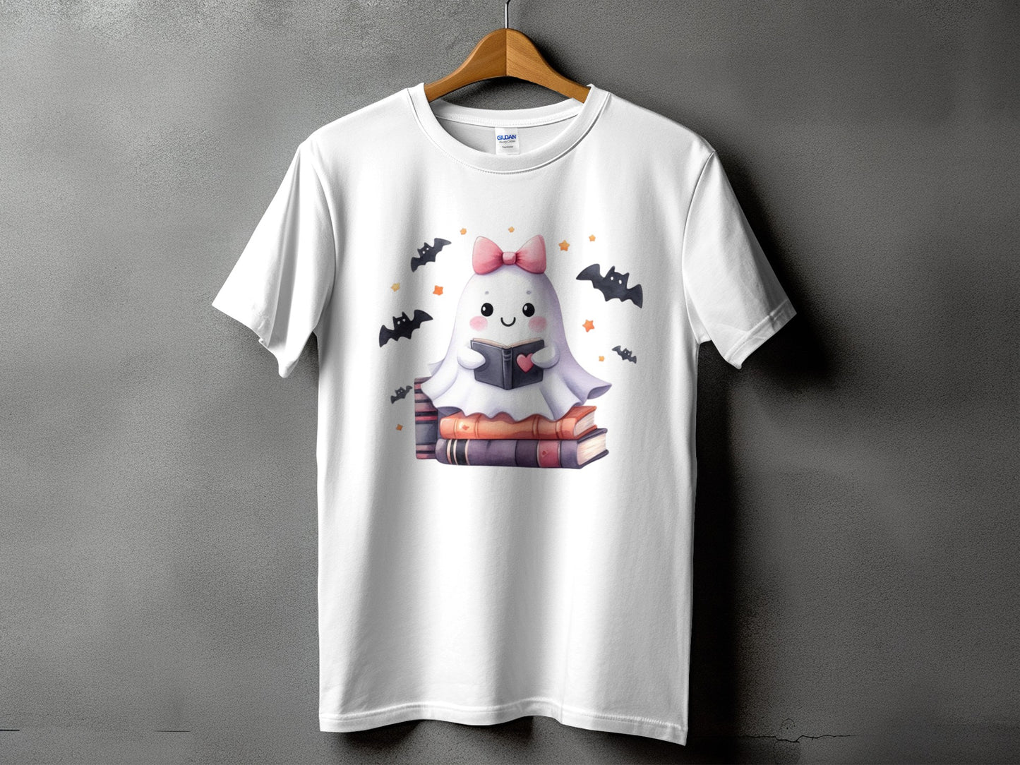 White t-shirt with a cute ghost reading a book surrounded by bats and stars.