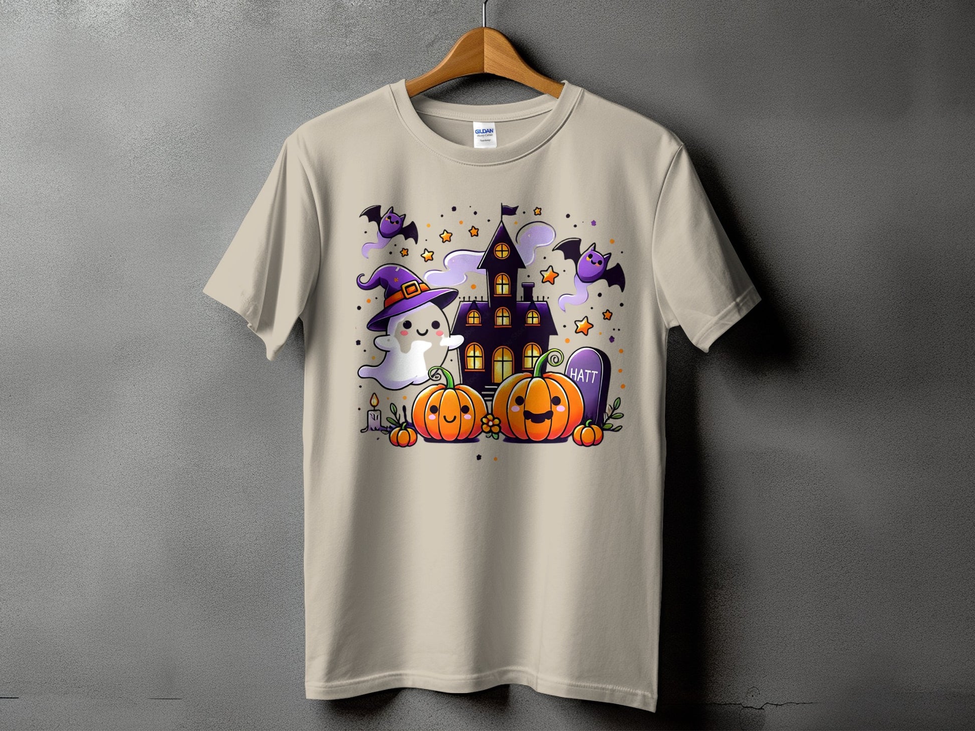 T-shirt with cute Halloween graphic featuring ghost, pumpkins, bats, and haunted house.