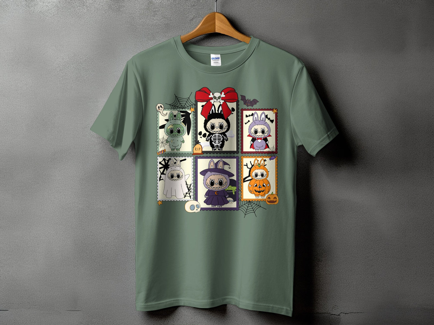 Green t-shirt with six Halloween-themed cartoon stamps featuring cute monsters and bats.