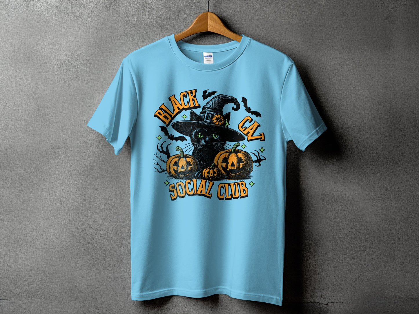 Light blue t-shirt with a black cat wearing a witch hat, pumpkins, and bats graphic.