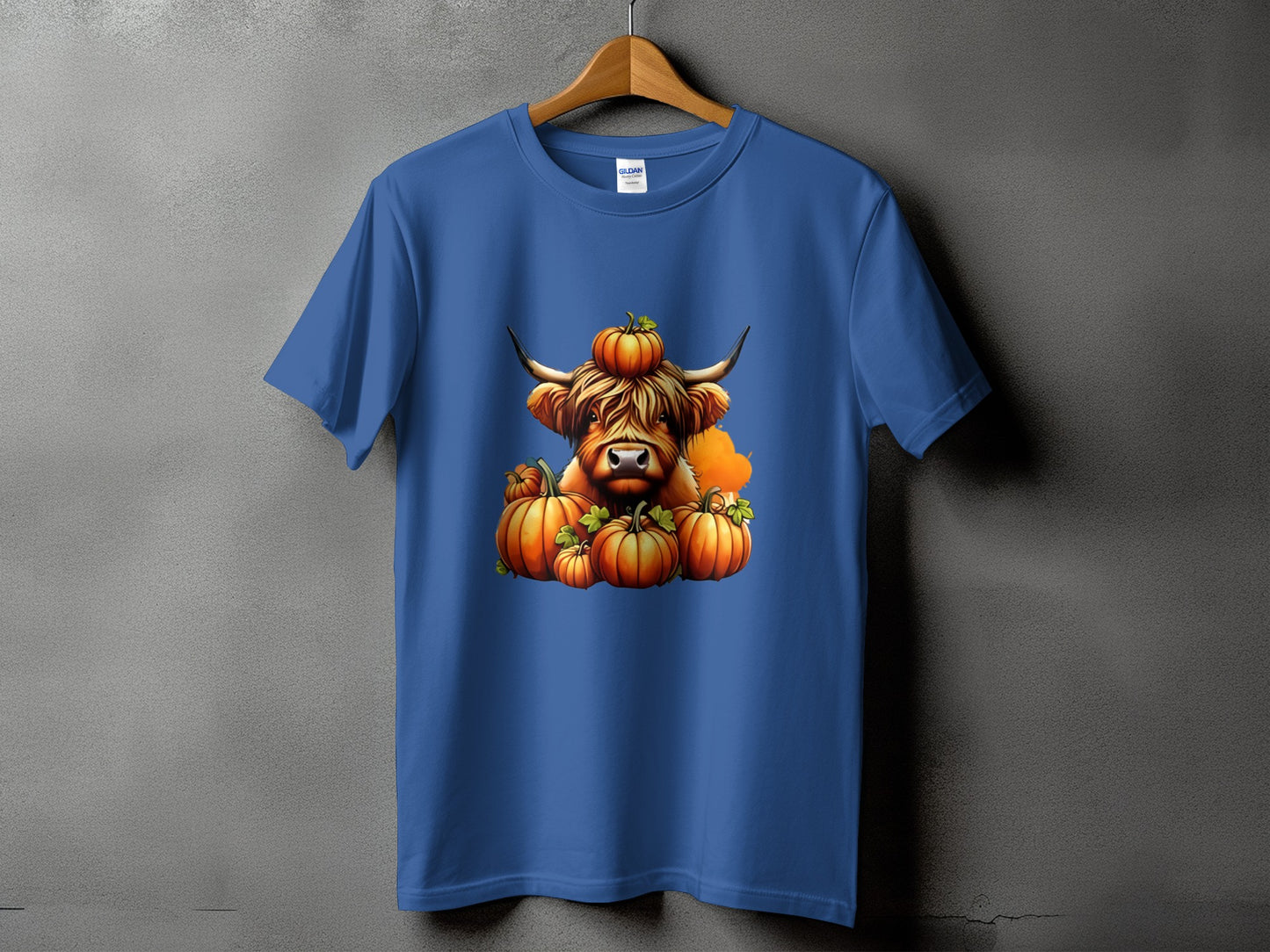 Blue t-shirt with a Highland cow illustration surrounded by pumpkins.