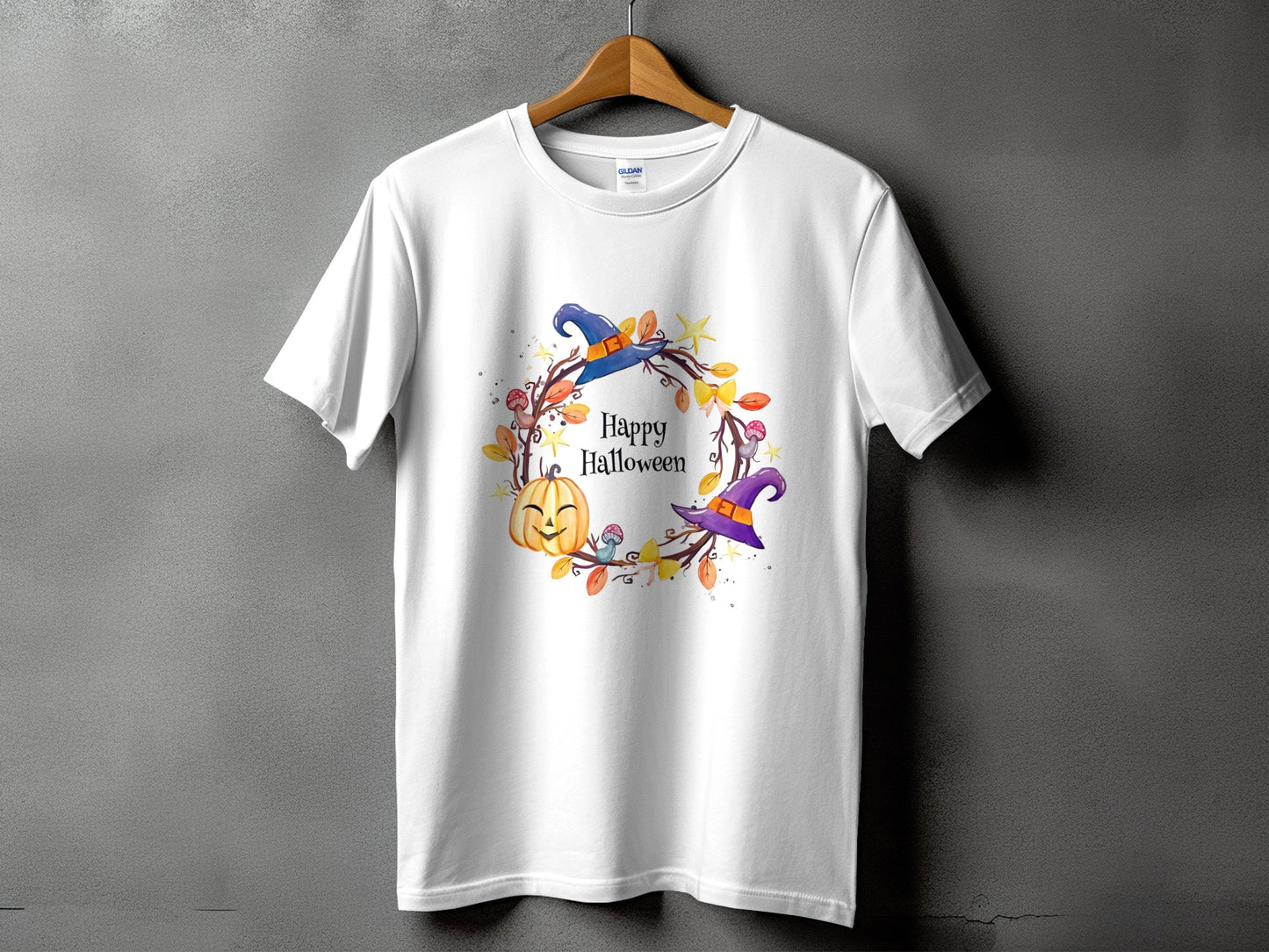 White t-shirt with a watercolor Halloween wreath featuring a pumpkin and witch hats.